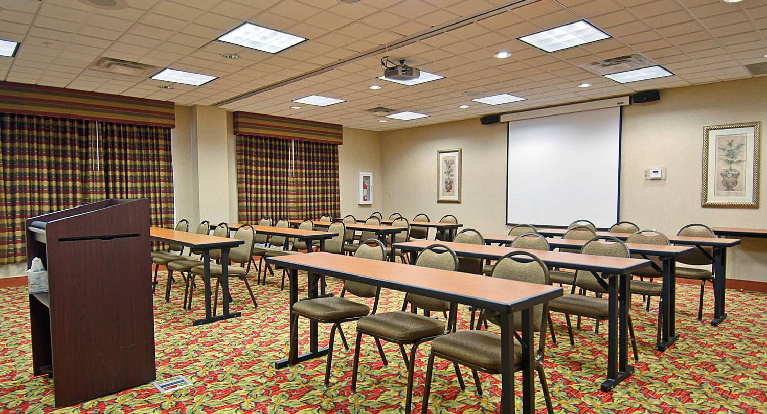 classroom style chairs and tables with a white projection screen pulled down
