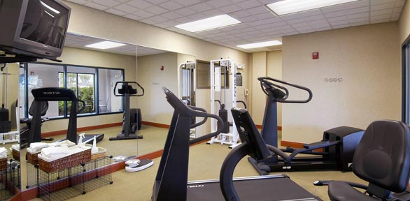 fitness center with treadmill, bikes, weight machine, large mirrors and TV 